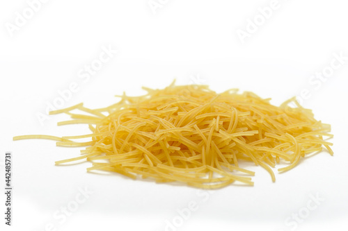 A small pile of yellow short pasta, vermicelli on a white background