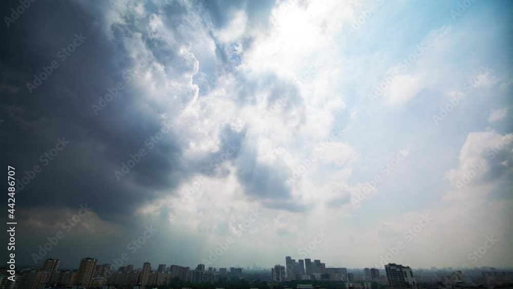 Beautiful timelapse of changing weather over the city from white fluffy clouds with sun rays to heavy thunderclouds and totally dark sky at the end.