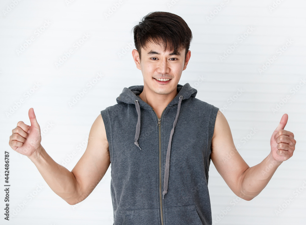 Smiling man holding hand thumbs up happy gesture wearing sleeveless t-shirt gray sportswear in white background.