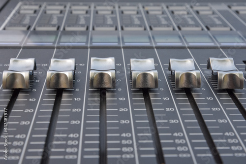 Close up of the silver faders of an audio mixer with gray background