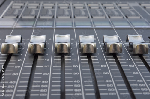 Close up of the silver faders of an audio mixer with gray background photo