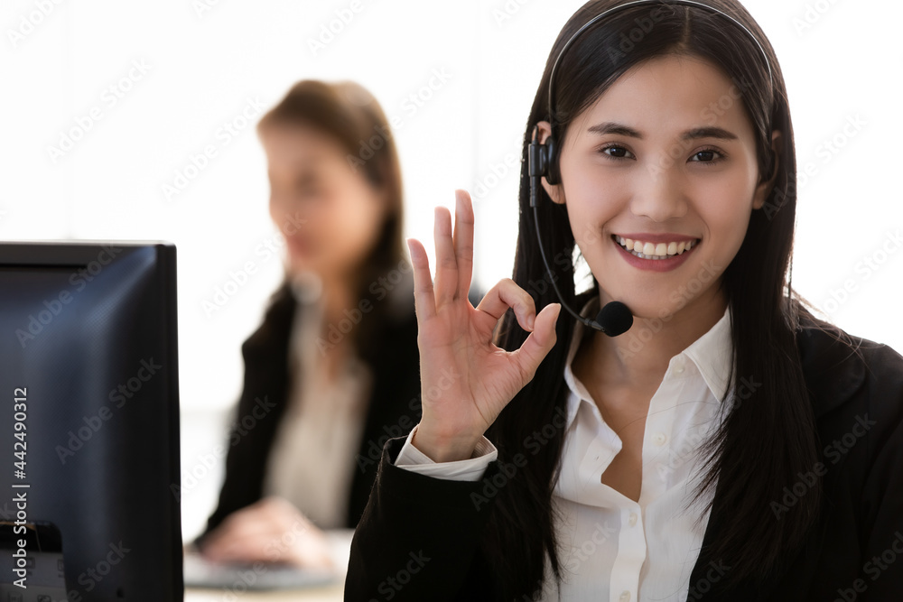 Two beautiful Asian women call center officer wearing microphone headset and happy working and rise hand with OK symbol signal in a friendly face and positive service mind Two beautiful Asian women call center officer wearing microphone headset and happy working and rise hand with OK symbol signal in a friendly face and positive service mind