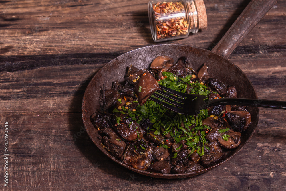 Fried royal champignons in an old cast-iron skillet with trendy hard light, dark shadow Fried royal champignons in an old cast-iron skillet with trendy hard light, dark shadow