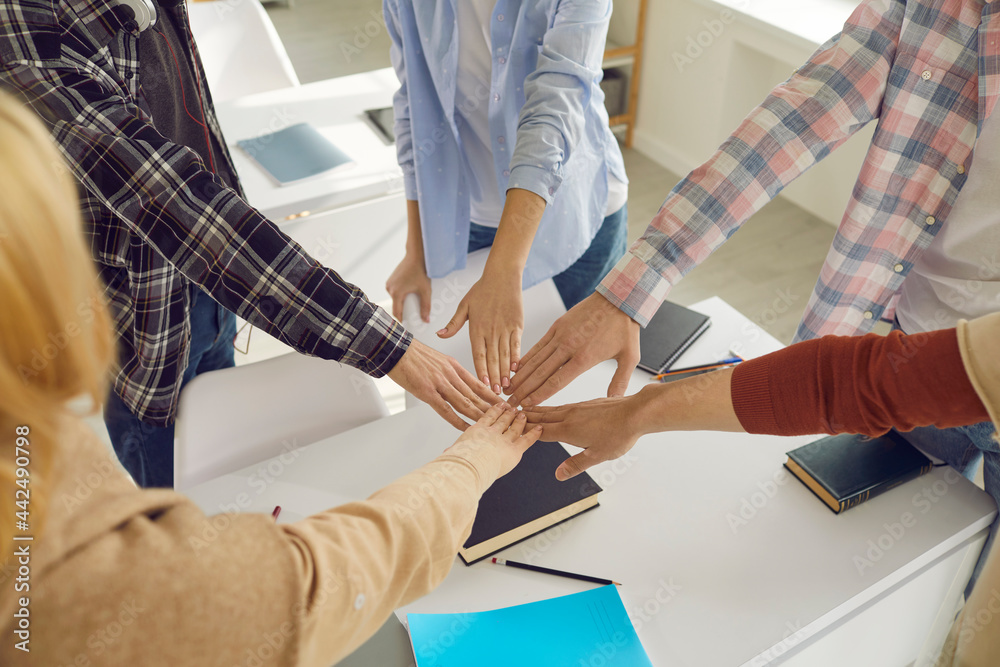 Unity and knowledge are power. Group of high school or college students join hands in circle over classroom desk taking friendship vow or team oath, swearing and promising to always support each other Unity and knowledge are power. Group of high school or college students join hands in circle over classroom desk taking friendship vow or team oath, swearing and promising to always support each other