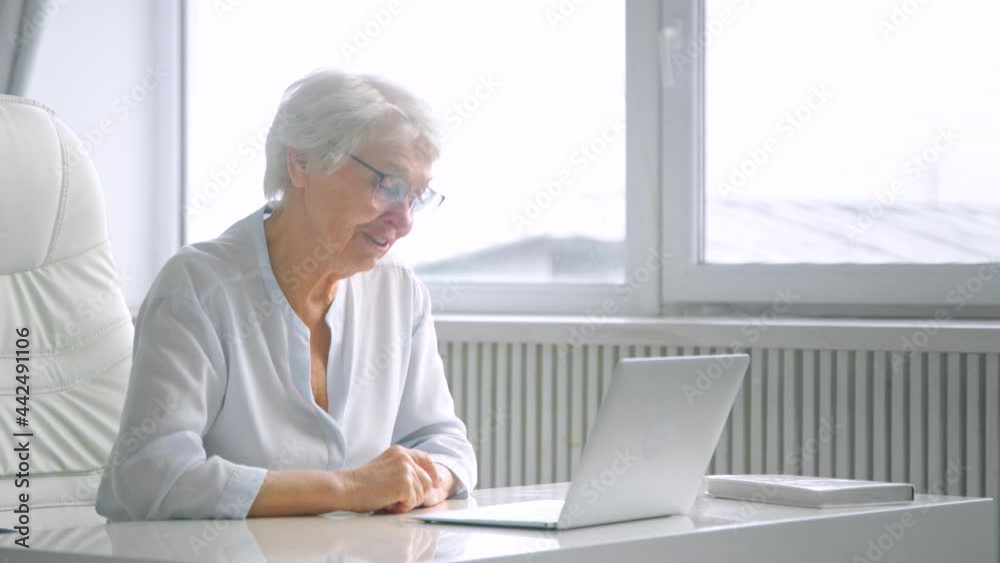 Smiling senior company lady worker waves hand and talks Smiling senior company lady worker waves hand and talks