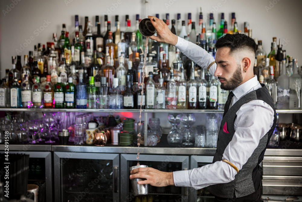 Skilled barman with shaker preparing cocktail