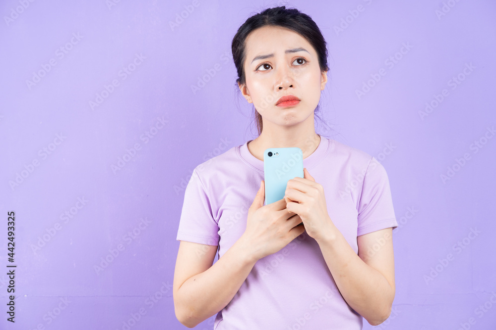 Young Asian woman using smartphone on purple background Young Asian woman using smartphone on purple background
