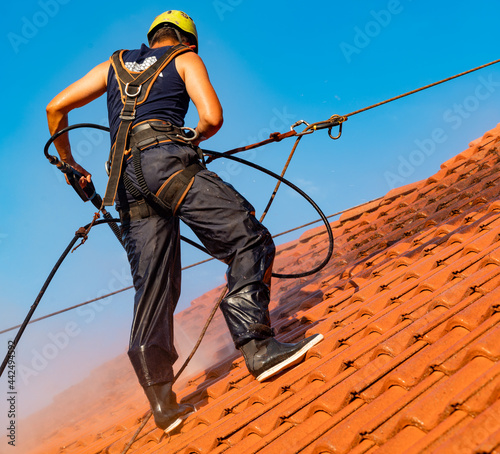 worker washing the roof with pressurized water photo