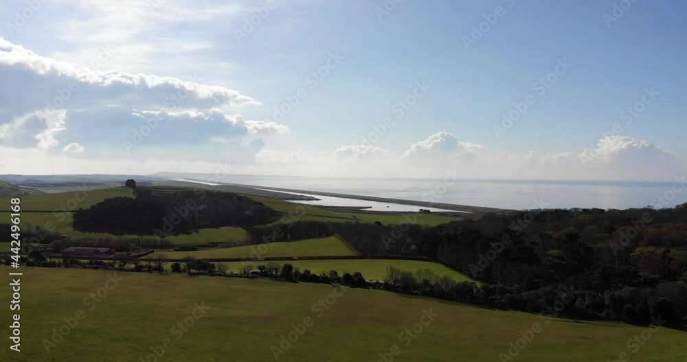 Aerial shot flying over fields and grass with a beach and coast in the background Aerial shot flying over fields and grass with a beach and coast in the background