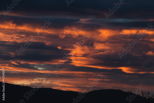 sunset sky with pink and orange clouds over the mountains © faithie