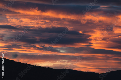 sunset sky with pink and orange clouds over the mountains © faithie