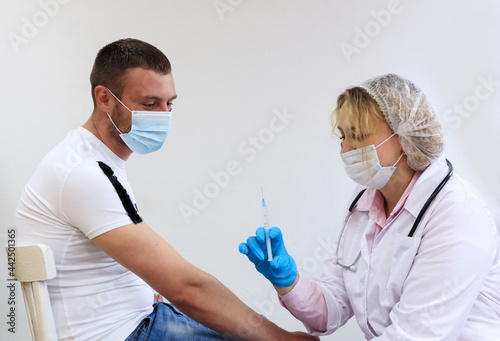 The concept of vaccination of the population. A female doctor injects a vaccine to a male patient, side view