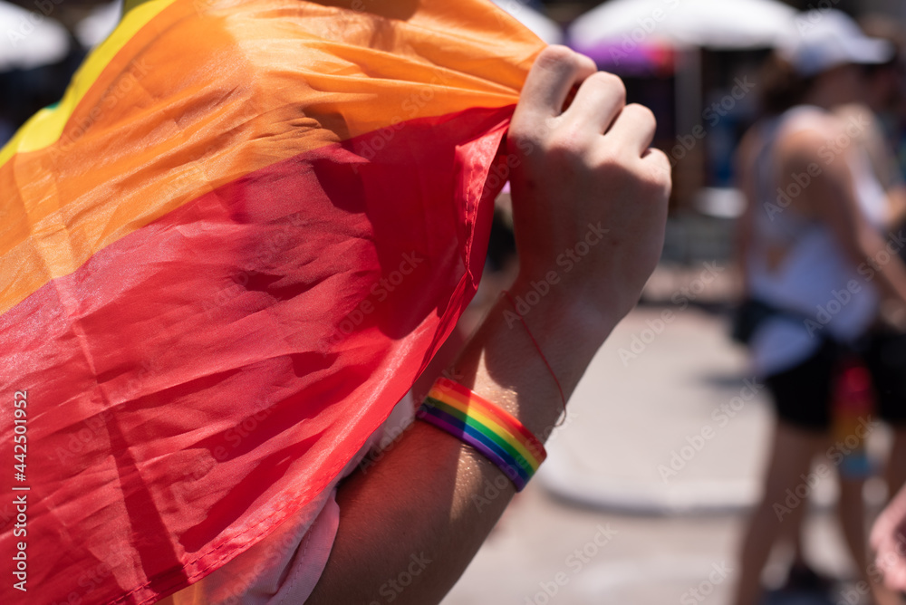 Obraz premium Man drees on hand bracelet of colors of rainbow. Close-up. Symbol of gays is colors of rainbow. Gay and pride solidarity parade in Tel Aviv.