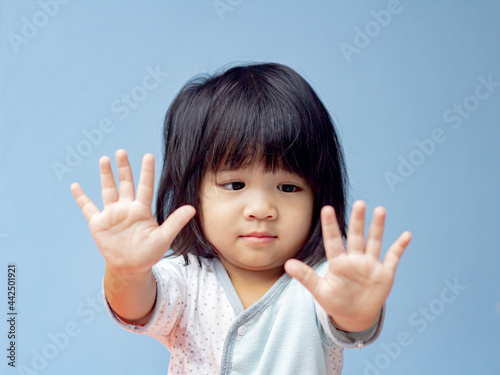 A headshot portrait of a cheerful baby Asian woman, a cute toddler little girl with adorable bangs hair, a child smiling and pose for hand don't looking to the camera.
