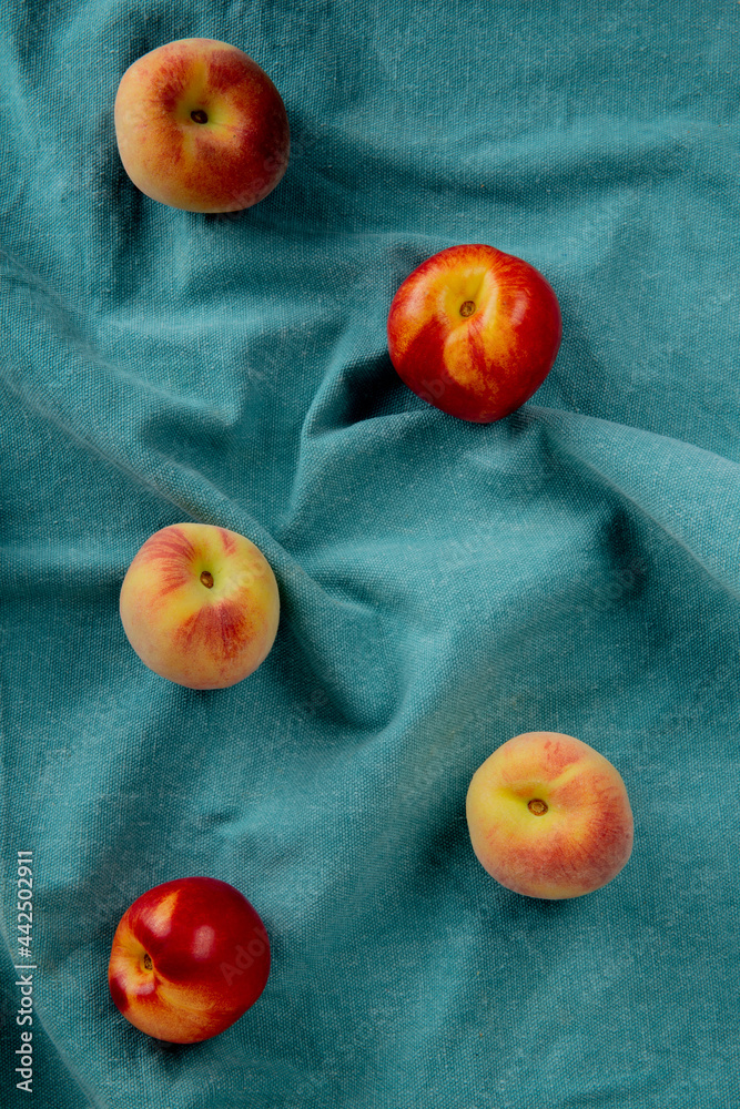 top view of fresh ripe nectarines and peaches scattered on blue fabric top view of fresh ripe nectarines and peaches scattered on blue fabric