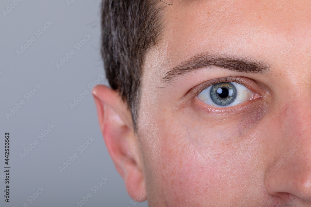 Close up of blue eye of caucasian businessman, isolated on grey background
