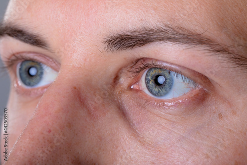 Close up of blue eyes of caucasian businessman, isolated on grey background