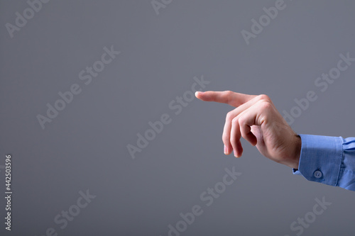 Midsection of caucasian businessman pointing with his finger, isolated on grey background photo