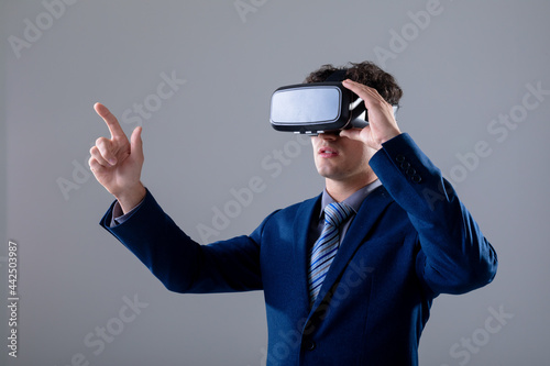 Caucasian businessman wearing vr headset touching virtual interface, isolated on grey background
