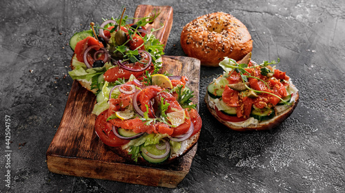 Food banner sandwich salad New York bagel with cream cheese, lettuce, cucumber, capers, onions and salted red fish. Excellent delicious breakfast or snack on cutting board. Copy space