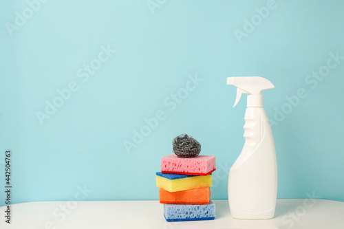 white bottle with cleaning procuct and sponges on blue background with empty space for text photo