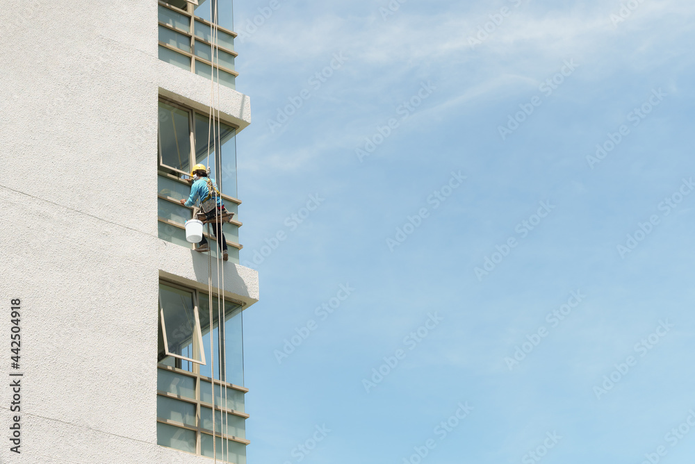 Out door shot of unknown painter labor abseiling to maintenance the building outdoor, Renovation and construction service professional worker on duty. Building improvement services. Out door shot of unknown painter labor abseiling to maintenance the building outdoor, Renovation and construction service professional worker on duty. Building improvement services.