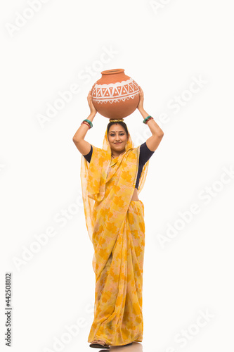 A woman standing with a matki on her head. photo