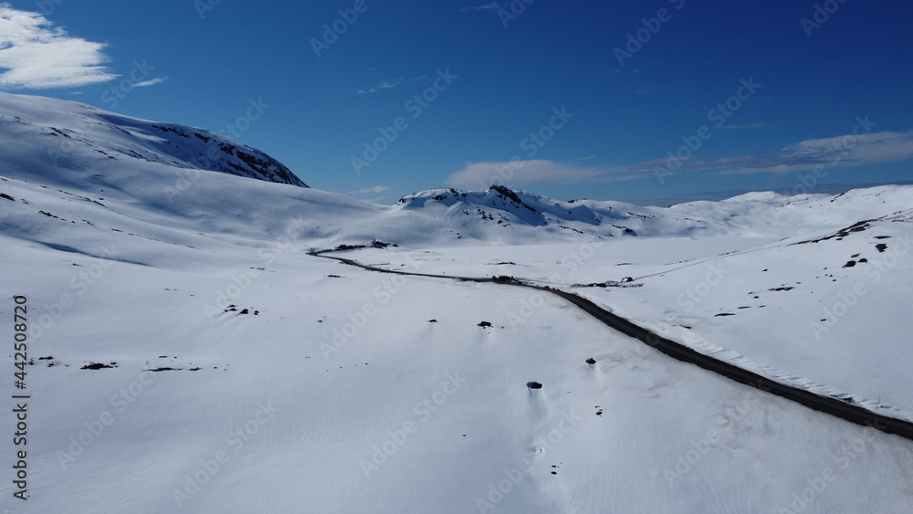 Breathtaking mountain landscape with clear blue skies and mountain road on the mountain pass of Kaperdalen on the island of Senja in northern Norway, aerial shot Breathtaking mountain landscape with clear blue skies and mountain road on the mountain pass of Kaperdalen on the island of Senja in northern Norway, aerial shot