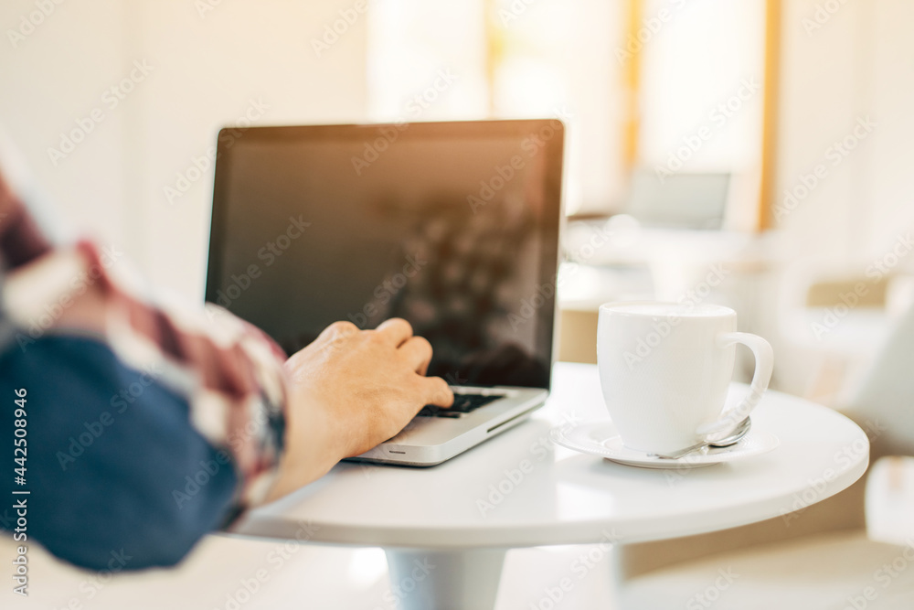 Man using laptop in cafe sitting on wooden table, male hands are typing on laptop keyboard Man using laptop in cafe sitting on wooden table, male hands are typing on laptop keyboard