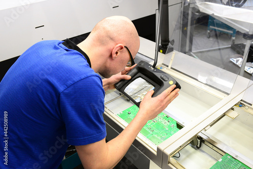 quality control in the production - man checks board for defects - manufacturing in a high tech factory