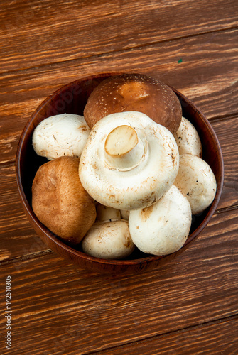 side view of fresh mushrooms in a wooden bowl on rustic background