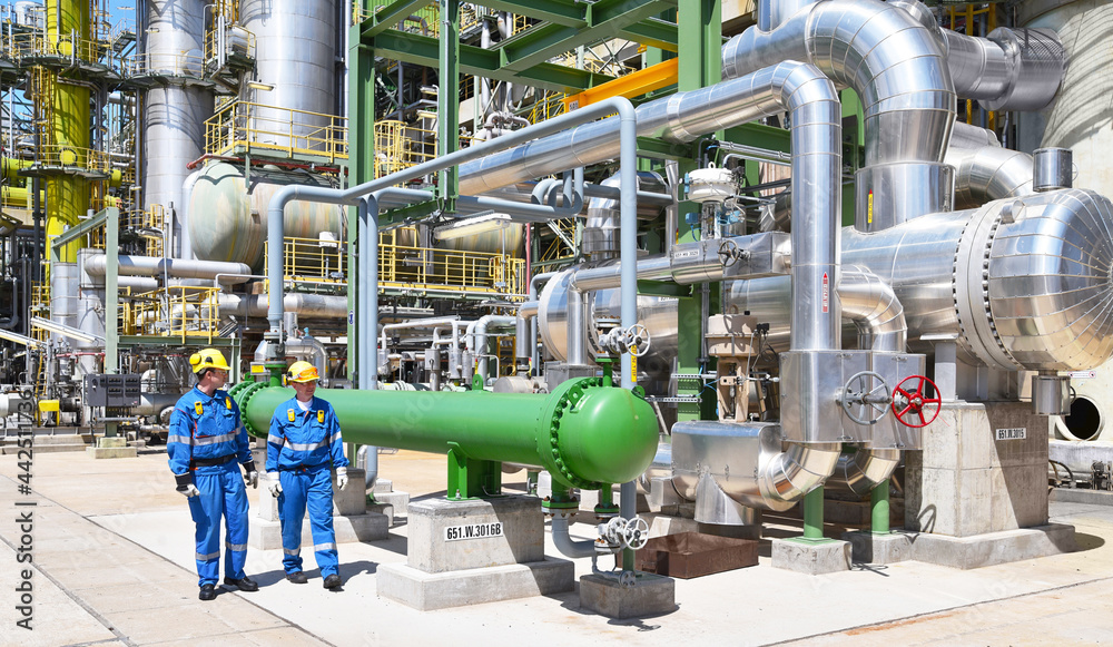 group of industrial workers in a refinery - oil processing equipment and machinery group of industrial workers in a refinery - oil processing equipment and machinery