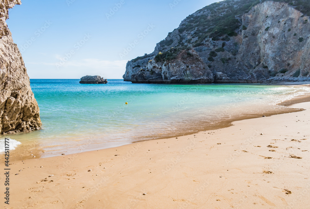 Ribeiro do Cavalo Beach with clear turquoise water with rocks and a ball floating in the water, Sesimbra PORTUGAL