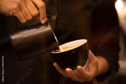 Close up hand pouring milk in coffee cup to make latte coffee