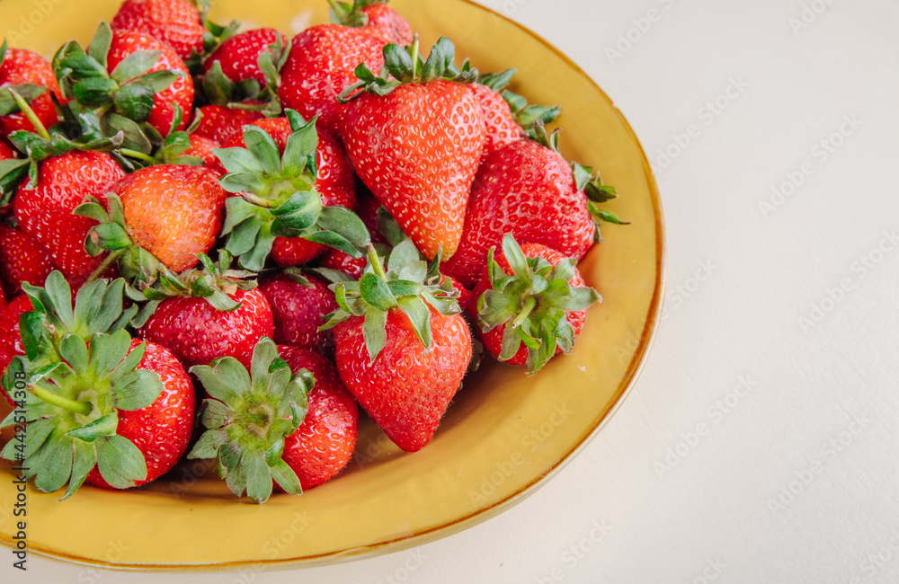side view of fresh ripe strawberries in a yellow plate on white background side view of fresh ripe strawberries in a yellow plate on white background