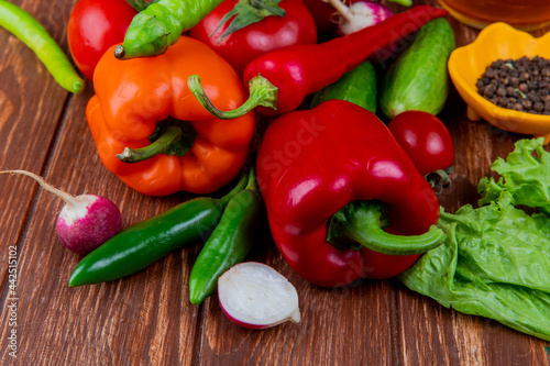 side view of fresh vegetables colorful bell peppers cucumbers ripe tomatoes green chili peppers radish and black peppercorns on wooden rustic background