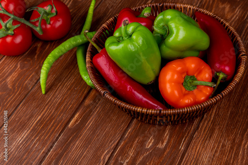 side view of fresh vegetables colorful bell peppers red chili peppers in a wicker basket on wooden rustic background