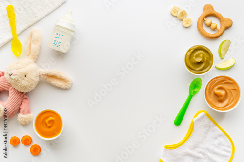 Bowls of various baby food and bottle of milk, top view photo