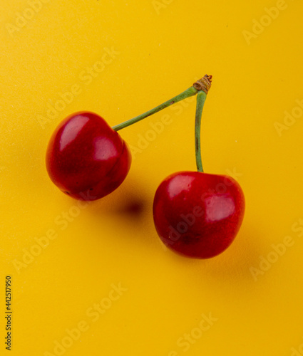 side view of red ripe cherry isolated on yellow background