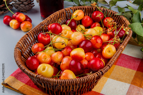 side view of ripe rainier cherries in a wicker basket on plaid napkin on the table photo