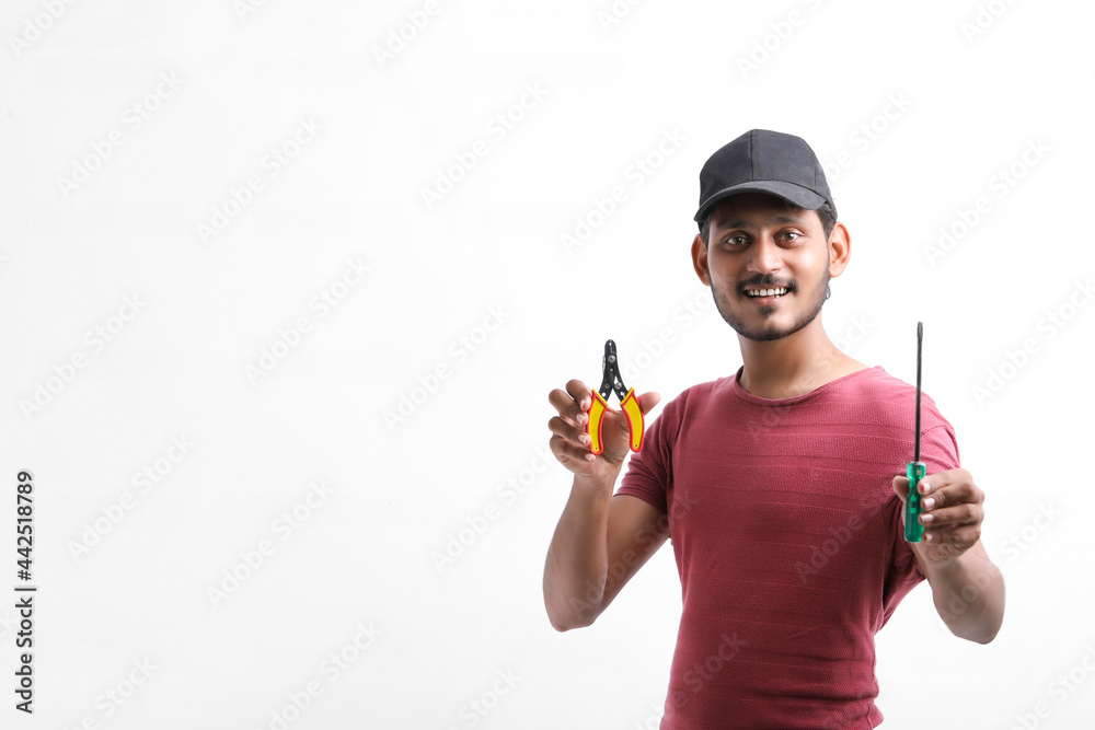 Young indian electrician holding tools in hand and standing over white background. Young indian electrician holding tools in hand and standing over white background.