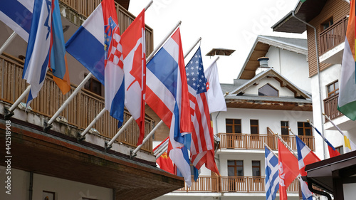 Many national flags of different states hang and blowing on building. Worldwide. International Flags are flying on building. American, Thai, Croatian, Slovak, Canadian, Greek, Israeli Flags.