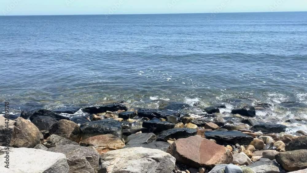Close up of ocean waves rolling on to the coast with large rocks in Rhode Island.