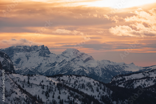 Dramatic colors effect of winter panorama of Pale di San Martino Peaks at sunset with sunlit clouds. Fiorentina Valley, Dolomites, Italy
