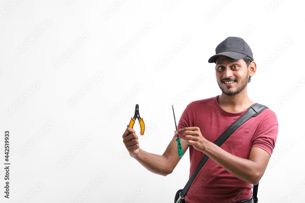 Young indian electrician holding tools in hand and standing over white background.
