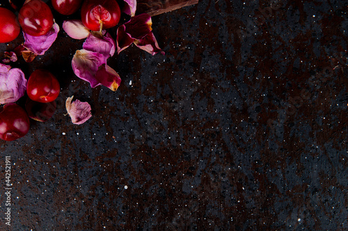 Fototapeta Naklejka Na Ścianę i Meble -  top view of  fresh red cherries with rose petals on dark background with copy space