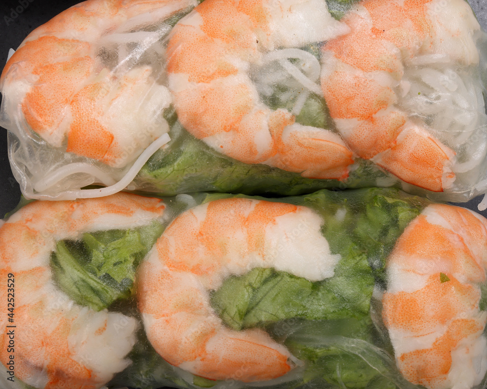 Vietnamese prawn shrimp see through rice paper spring roll green vegetable sauce on dark plate Vietnamese prawn shrimp see through rice paper spring roll green vegetable sauce on dark plate