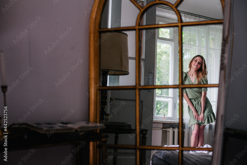 Young, slender girl reflected in an old mirror