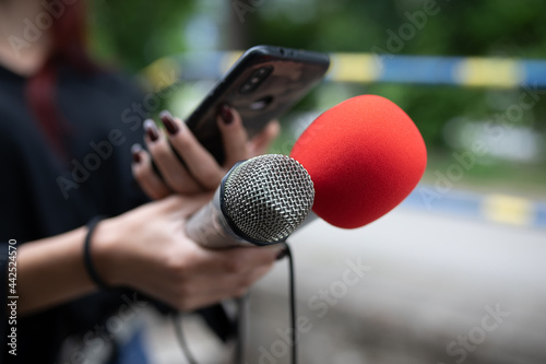 Journalist at news conference, recording notes, holding microphones and smartphone dictaphone