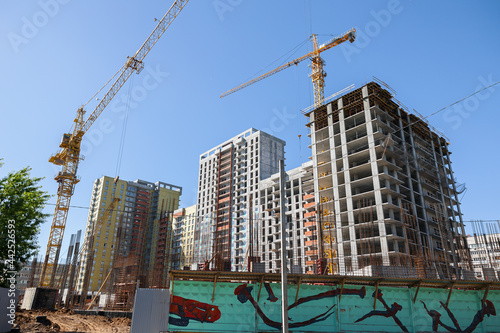 A high-rise building is under construction. metal and concrete structures. Yellow construction crane. A sunny summer day.